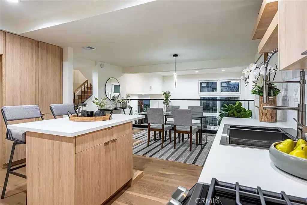 The heart of this home is undoubtedly the custom kitchen, featuring quartz counters, stainless steel appliances, and a center island that effortlessly flows into the dining area with a view down to the living room through custom glass railing
