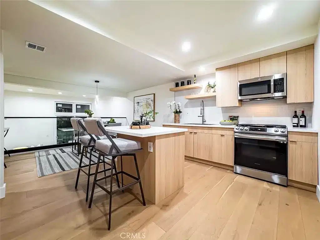 The heart of this home is undoubtedly the custom kitchen, featuring quartz counters, stainless steel appliances, and a center island that effortlessly flows into the dining area with a view down to the living room through custom glass railing